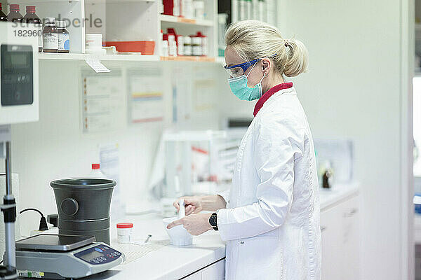 Wissenschaftler tragen eine schützende Gesichtsmaske und stellen im Labor Medikamente her