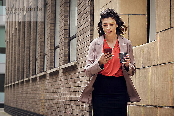 Geschäftsfrau nutzt Smartphone am Gebäude