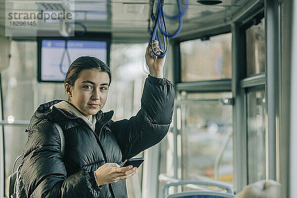 Lächelndes Teenager-Mädchen steht mit Smartphone in der Seilbahn