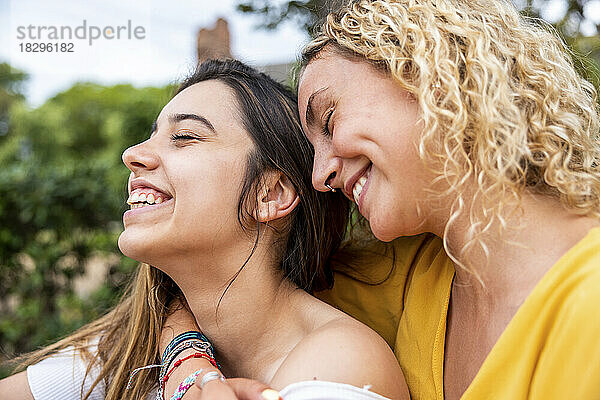Happy lesbian young couple with eyes closed in park