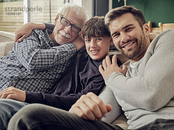 Glücklicher Großvater  Vater und Sohn sitzen zusammen auf der Couch im Wohnzimmer