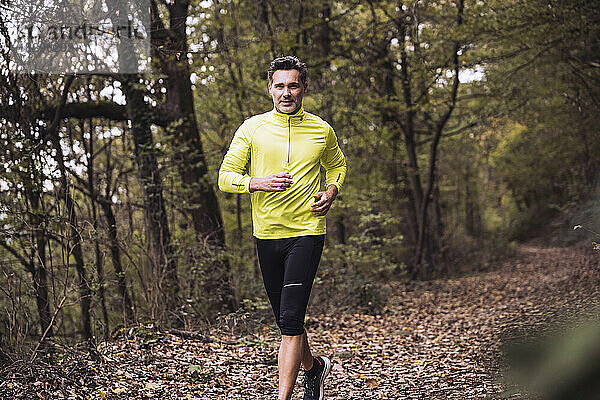 Lächelnder reifer Mann joggt im Wald