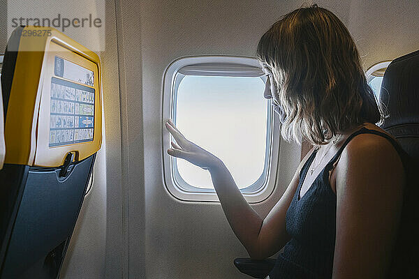Frau schaut durch Flugzeugfenster