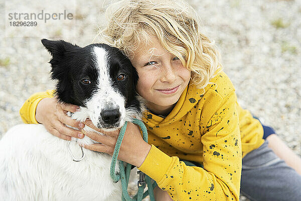 Happy blond boy embracing Border Collie dog