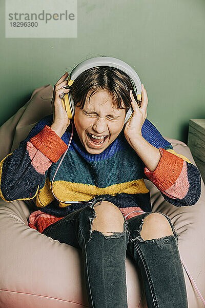 Girl wearing headphones screaming and sitting on bean bag