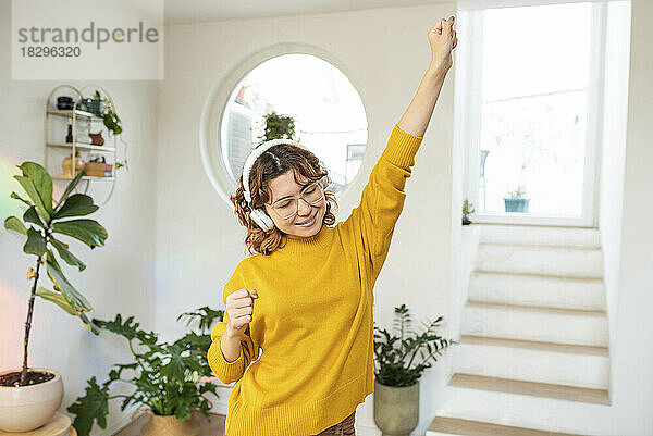 Lächelnde junge Frau  die Spaß beim Tanzen zu Hause hat