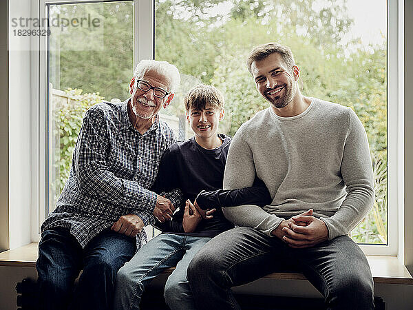 Glücklicher Großvater  Vater und Sohn sitzen zu Hause am Fenster