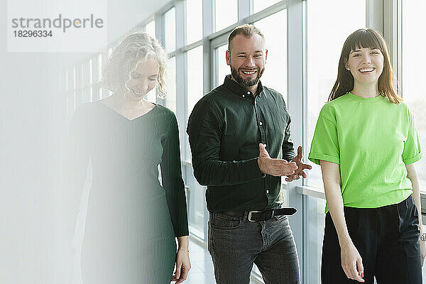 Drei glückliche Geschäftsleute in grüner Kleidung auf der Büroetage