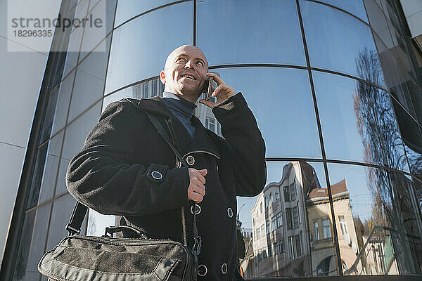 Reifer Geschäftsmann telefoniert vor dem Gebäude