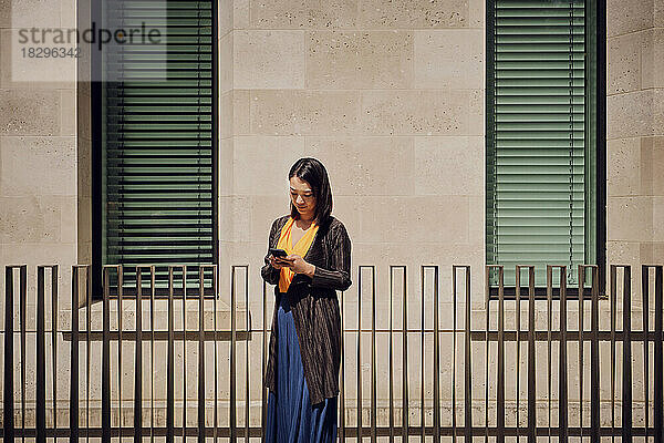 Geschäftsfrau benutzt Mobiltelefon an sonnigem Tag