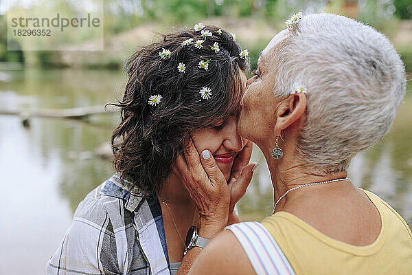 Ältere Frau küsst Freundin im Park auf die Stirn
