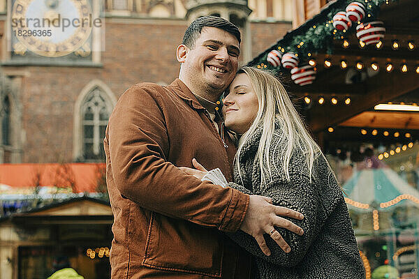 Happy man embracing woman at Christmas market
