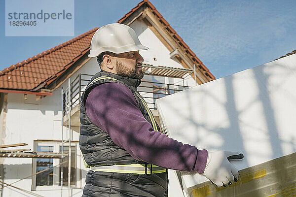 Bauarbeiter hält an sonnigem Tag Polystyrolschaum in der Hand