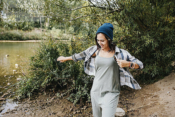 Lächelnde junge Frau in Strickkleidung verbringt ihre Freizeit im Park