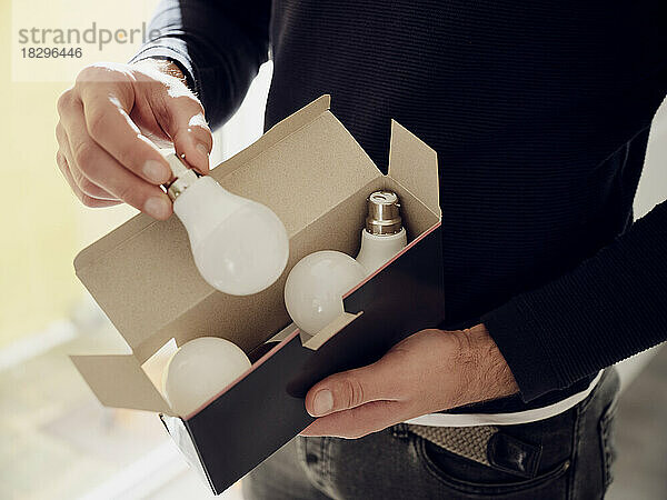 Close-up of man holding a box of LED lightbulbs