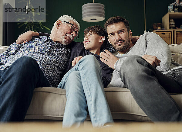 Großvater  Vater und Sohn sitzen zusammen auf der Couch im Wohnzimmer