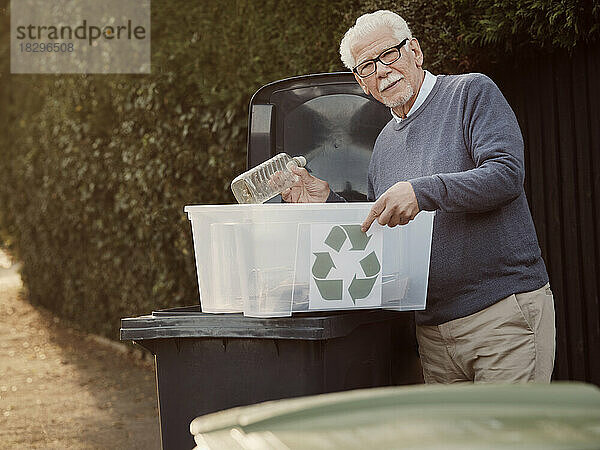 Älterer Mann wirft getrennten Recyclingabfall in den Mülleimer