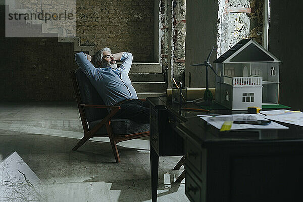 Architekt entspannt sich im Stuhl auf der Baustelle