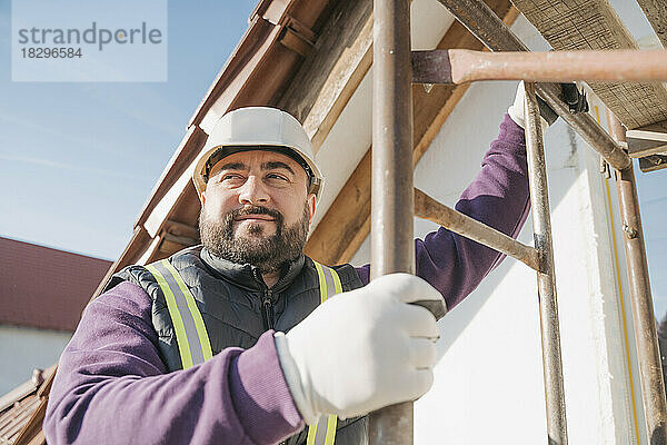 Lächelnder Bauarbeiter mit Leiter