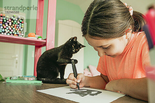 Mädchen zeichnet zu Hause ein Katzenbild auf Papier