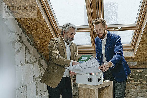 Lächelnde Geschäftsleute diskutieren auf der Baustelle über Baupläne