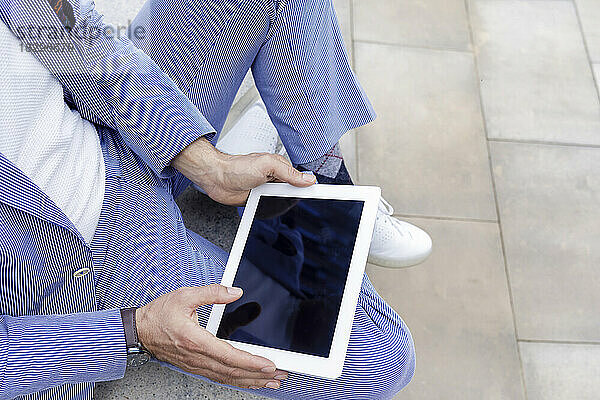 Hände eines Geschäftsmannes mit Tablet-PC  der auf einer Bank sitzt