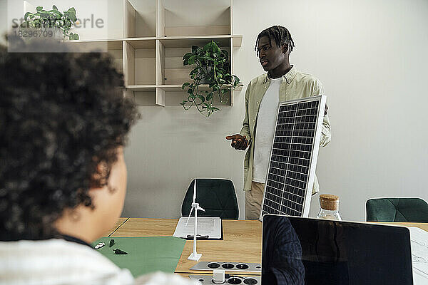 Geschäftsmann diskutiert mit Kollegen im Büro über Solarpanel