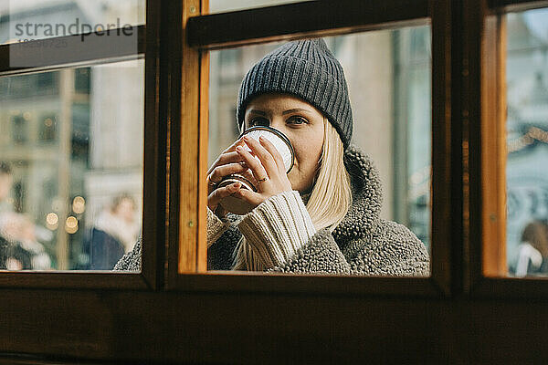 Frau trinkt Kaffee durch Glasfenster gesehen