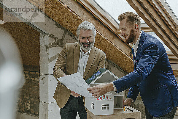 Lächelnde Architekten diskutieren auf der Baustelle über Baupläne