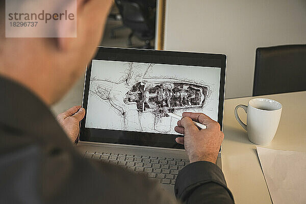 Geschäftsmann zeichnet Windturbinendesign auf Laptop am Schreibtisch