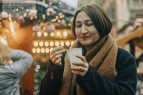 Lächelnde Frau  die im Winter Kaffee trinkt