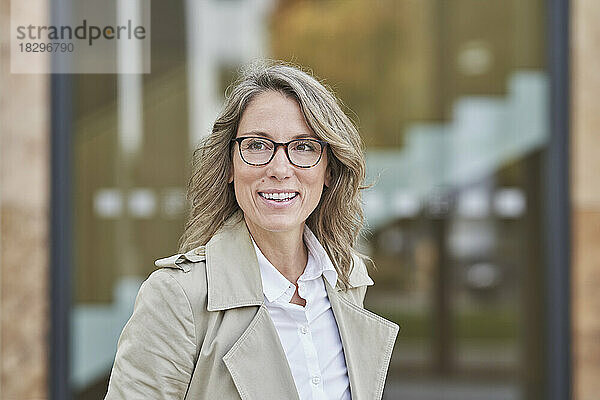 Glückliche reife Geschäftsfrau mit Brille vor dem Gebäude