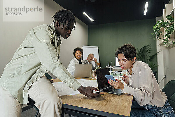 Geschäftskollegen diskutieren über Smartphones im Büro