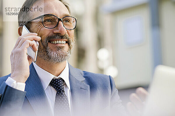 Lächelnder reifer Geschäftsmann  der am Smartphone spricht