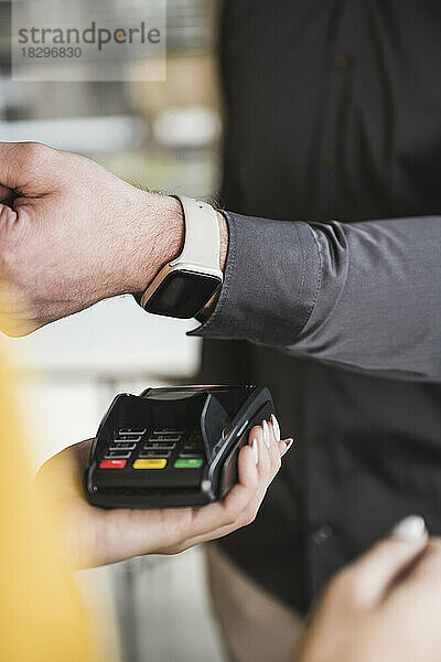 Geschäftsmann zahlt mit Smartwatch am Kartenlesegerät