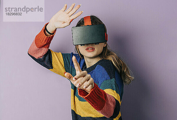 Mädchen mit VR-Simulator gestikuliert vor violettem Hintergrund