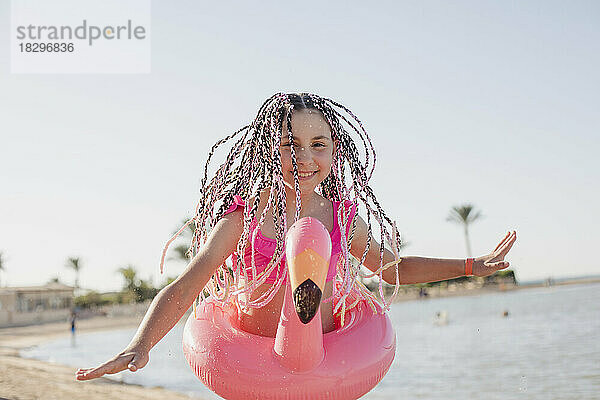 Glückliches Mädchen mit geflochtenen Haaren  das es am Strand genießt