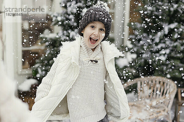 Glücklicher Junge  der Spaß im Schnee im Vorgarten hat