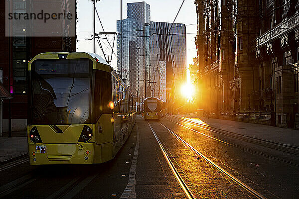 Großbritannien  England  Manchester  Seilbahnen fahren bei Sonnenuntergang entlang der Straße in der Innenstadt