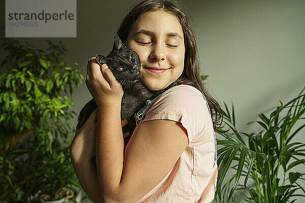 Smiling girl embracing cat at home