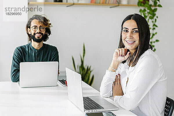 Lächelnder Geschäftsmann und Geschäftsfrau mit Laptop am Schreibtisch