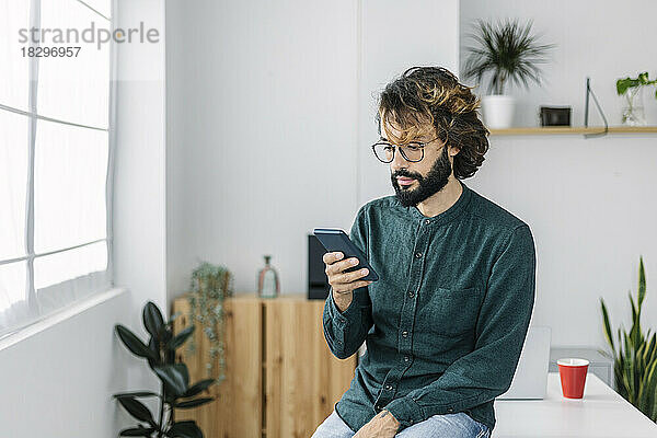 Freiberufler nutzt Smartphone am Schreibtisch im Büro