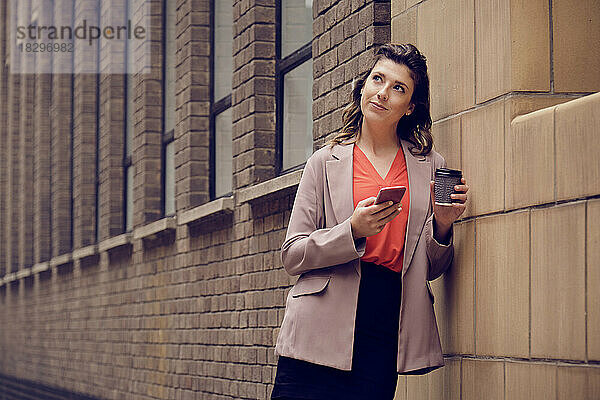 Nachdenkliche Geschäftsfrau mit Smartphone und Kaffeetasse