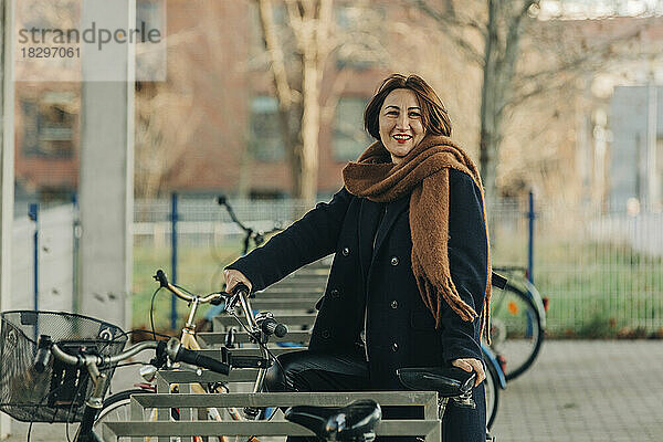 Lächelnde reife Frau mit Fahrrad am Parkplatz