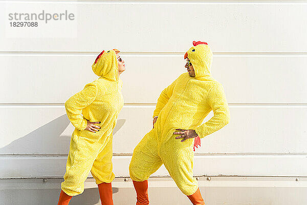 Freunde in Hühnerkostümen amüsieren sich vor der Wand