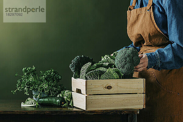 Frau legt frisches grünes Gemüse in Kiste