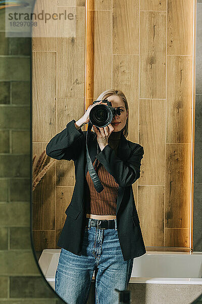 Frau fotografiert mit Kamera im Badezimmerspiegel