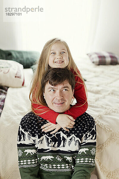 Lächelnder Vater mit Tochter  die auf dem Bett sitzt und zu Hause Spaß hat