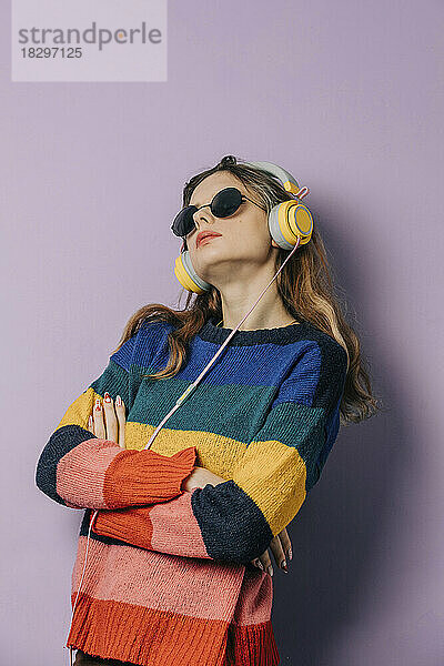 Mädchen hört Musik über Kopfhörer vor violettem Hintergrund
