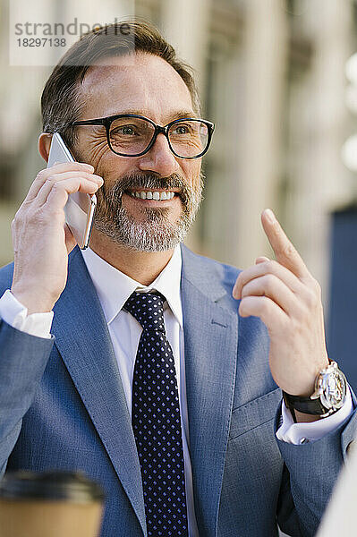 Glücklicher reifer Geschäftsmann mit Brille  der auf dem Handy spricht